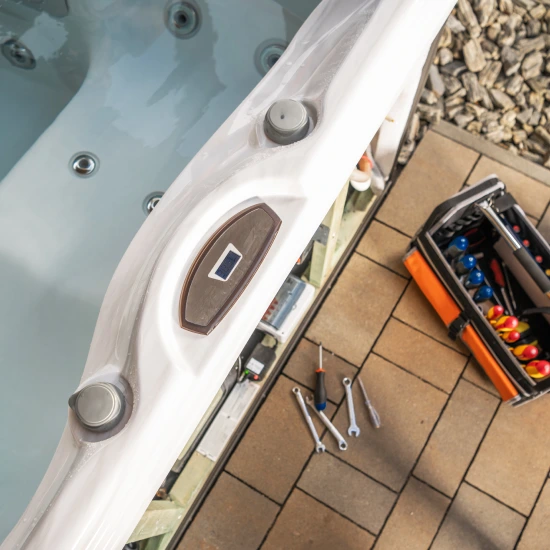 Hot Tub Repair Service - Hot tub being serviced with tools and an open toolbox laid out beside the spa on a patio surface.