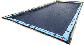Rectangular in-ground pool covered with a dark winter cover secured by water tubes around the edges.