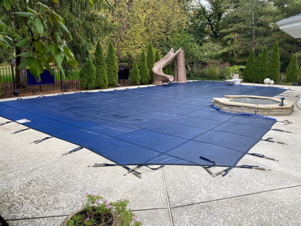 In-ground swimming pool and raised spa protected by a securely fastened safety cover.